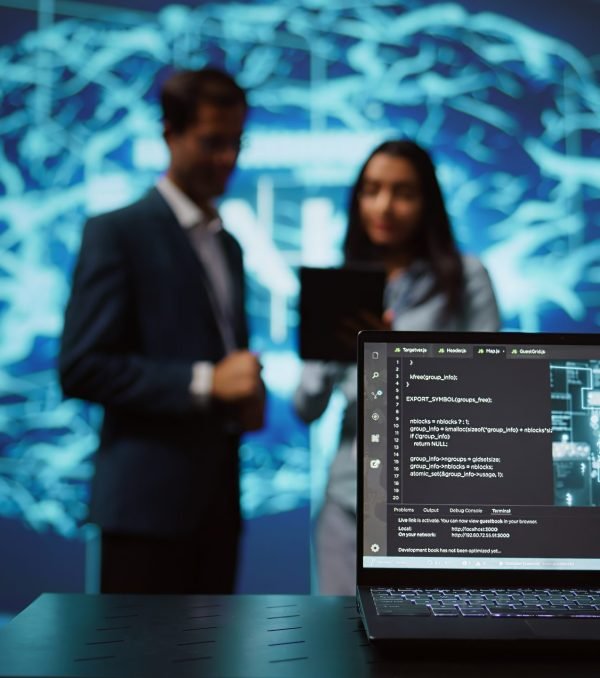 Focus on laptop in workspace used by AI researchers working with artificial intelligence in blurry background. Close up of notebook used by employees developing AI systems in tech startup, camera B