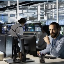 Technician using PC in data center to update server tech, configuring equipment using software tools. Server room employee reviewing hardware analytics, ensuring reliable network operations